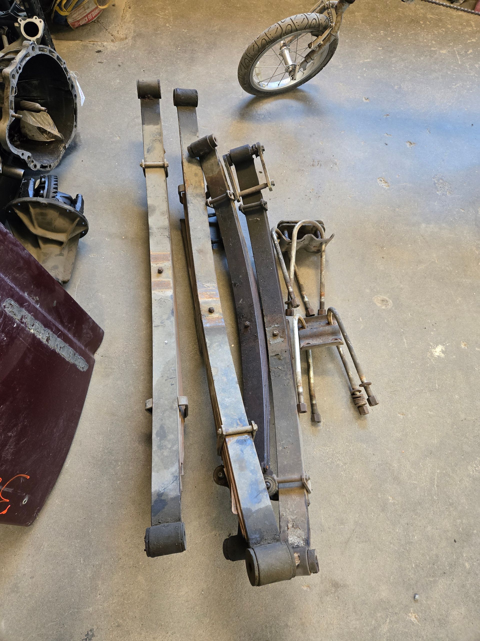 Leaf springs and other car parts on a garage floor.