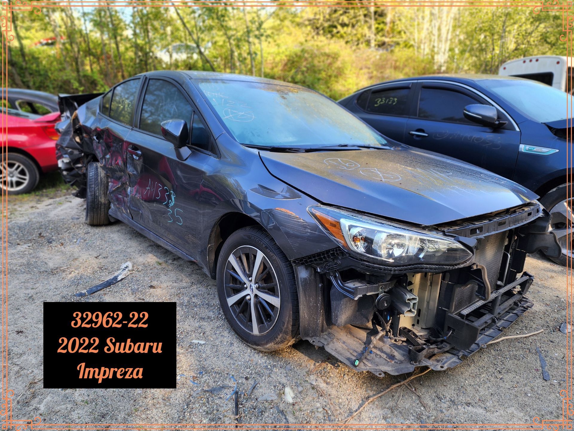 Damaged 2022 Subaru Impreza at a salvage yard, blue-gray with front-end collision damage.