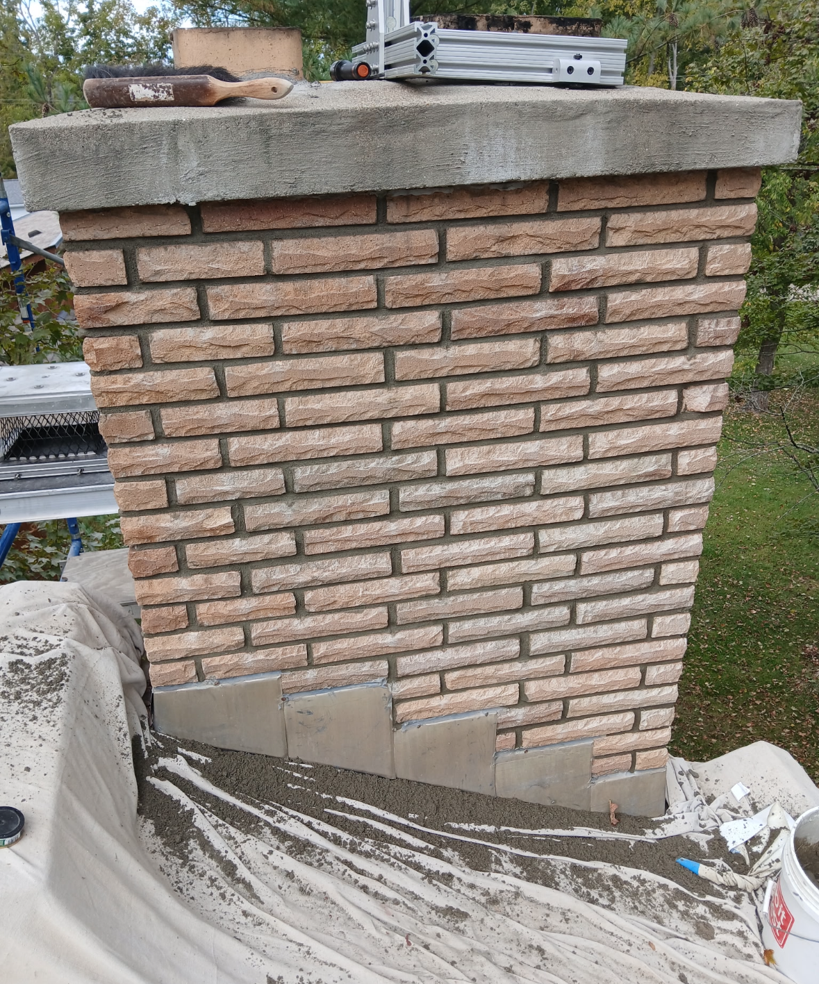 Chimney crown and clay flue tile with visible water staining before chimney cap installation