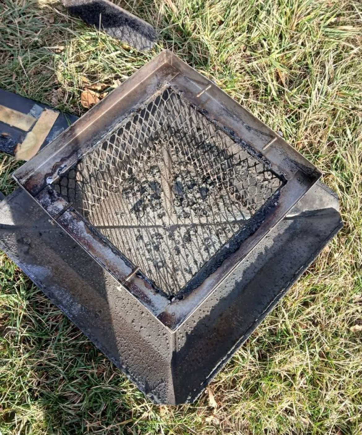 Removed chimney cap showing creosote buildup and flue opening before replacement