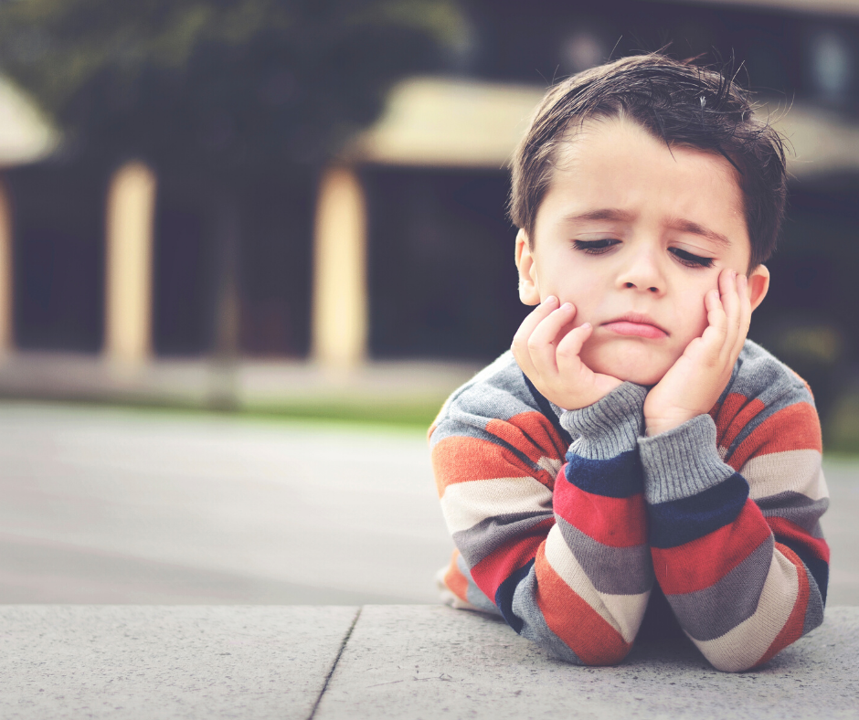 ילד שוכב על הדשא מחזיק את הראש עם פרצוף עצוב