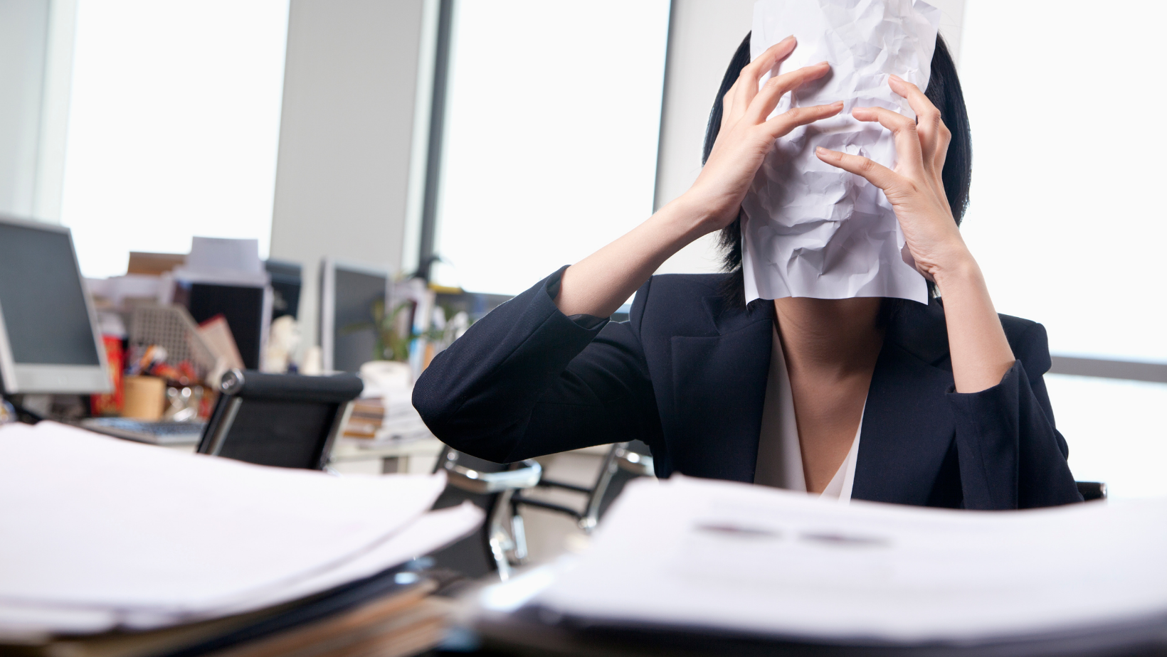 אישה מחזיקה דף נייר על הפנים במשרד