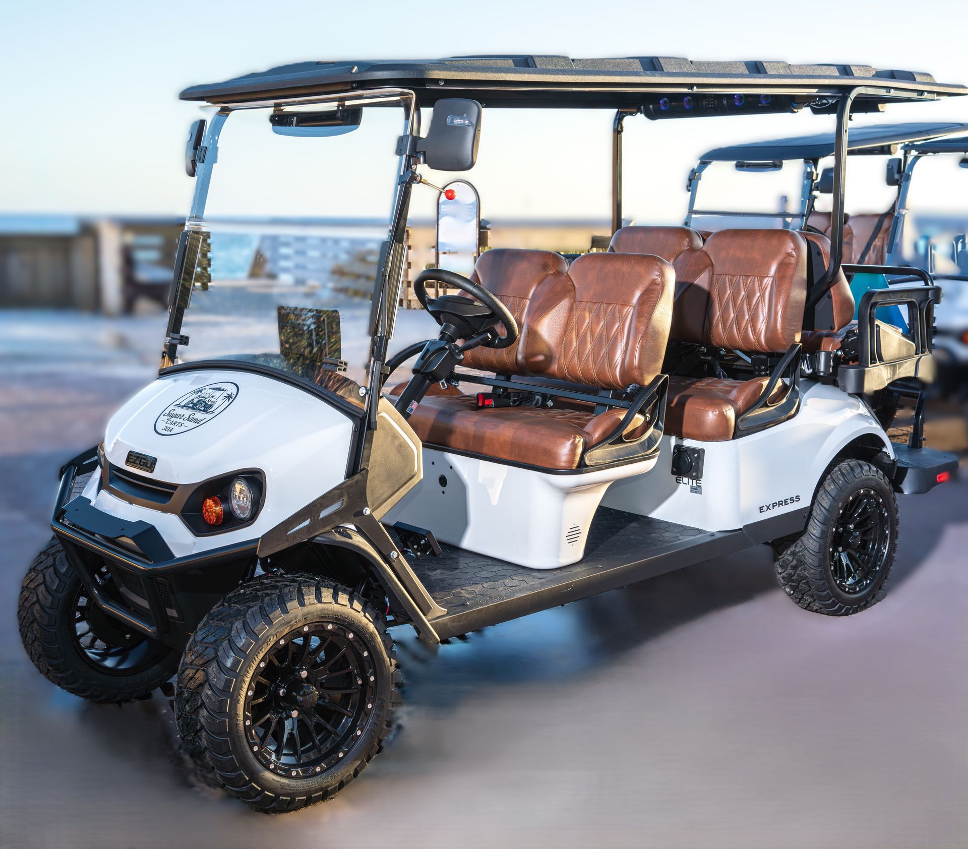 A white golf cart with brown quilted leather seats parked on a paved surface.
