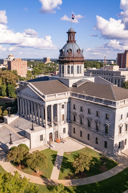 A wooden walkway leading to a gazebo overlooking a body of water at sunset.