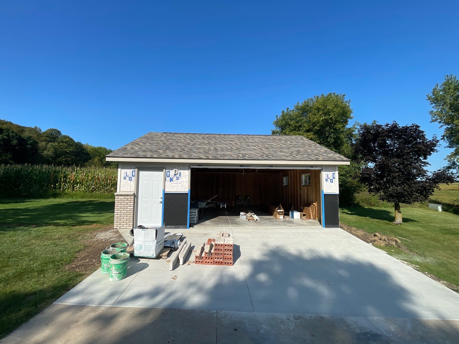 A garage is being built in the middle of a grassy field.