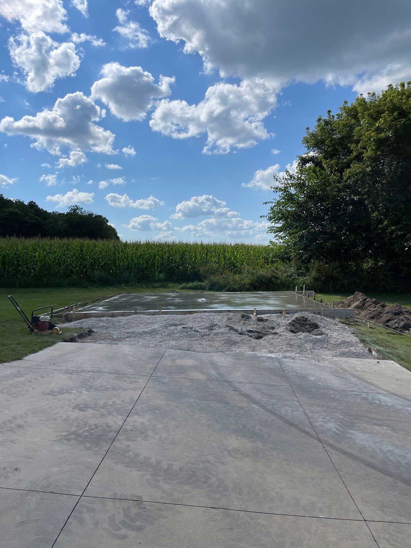 A concrete driveway with a field of corn in the background