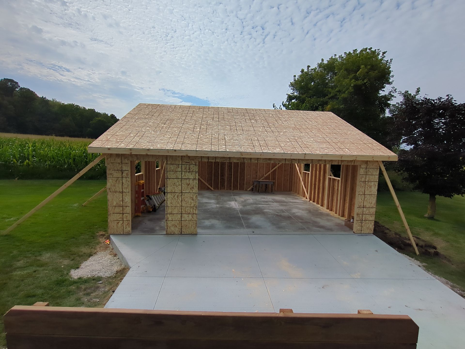 A garage is being built in the middle of a grassy field.