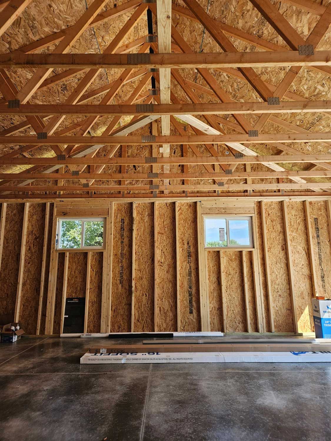 The inside of a garage under construction with wooden beams and windows.