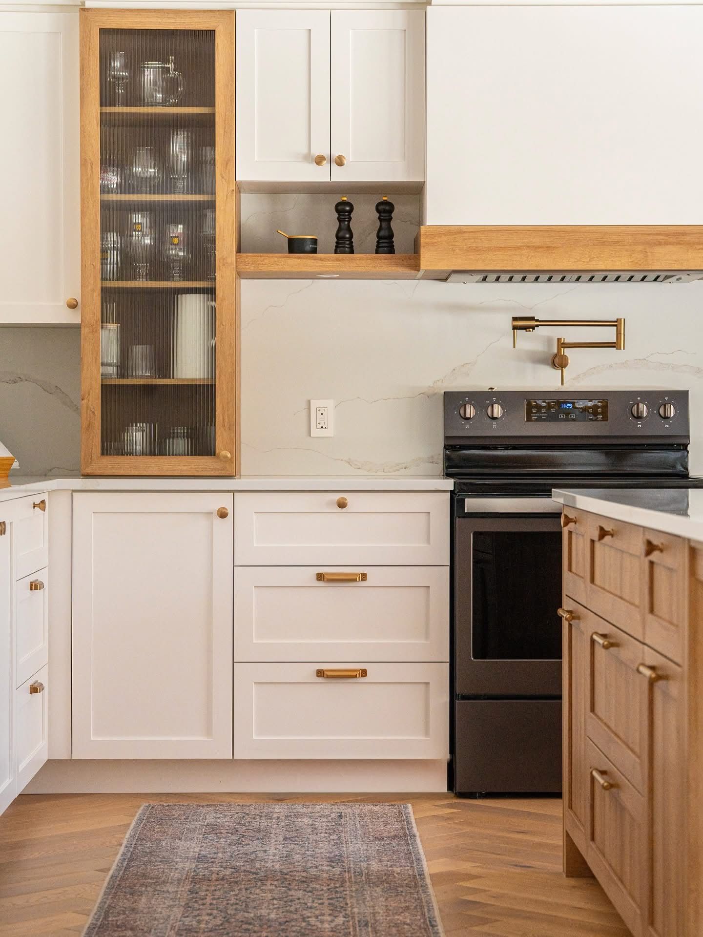 Cuisine moderne avec armoires blanches, accents en bois et cuisinière foncée.
