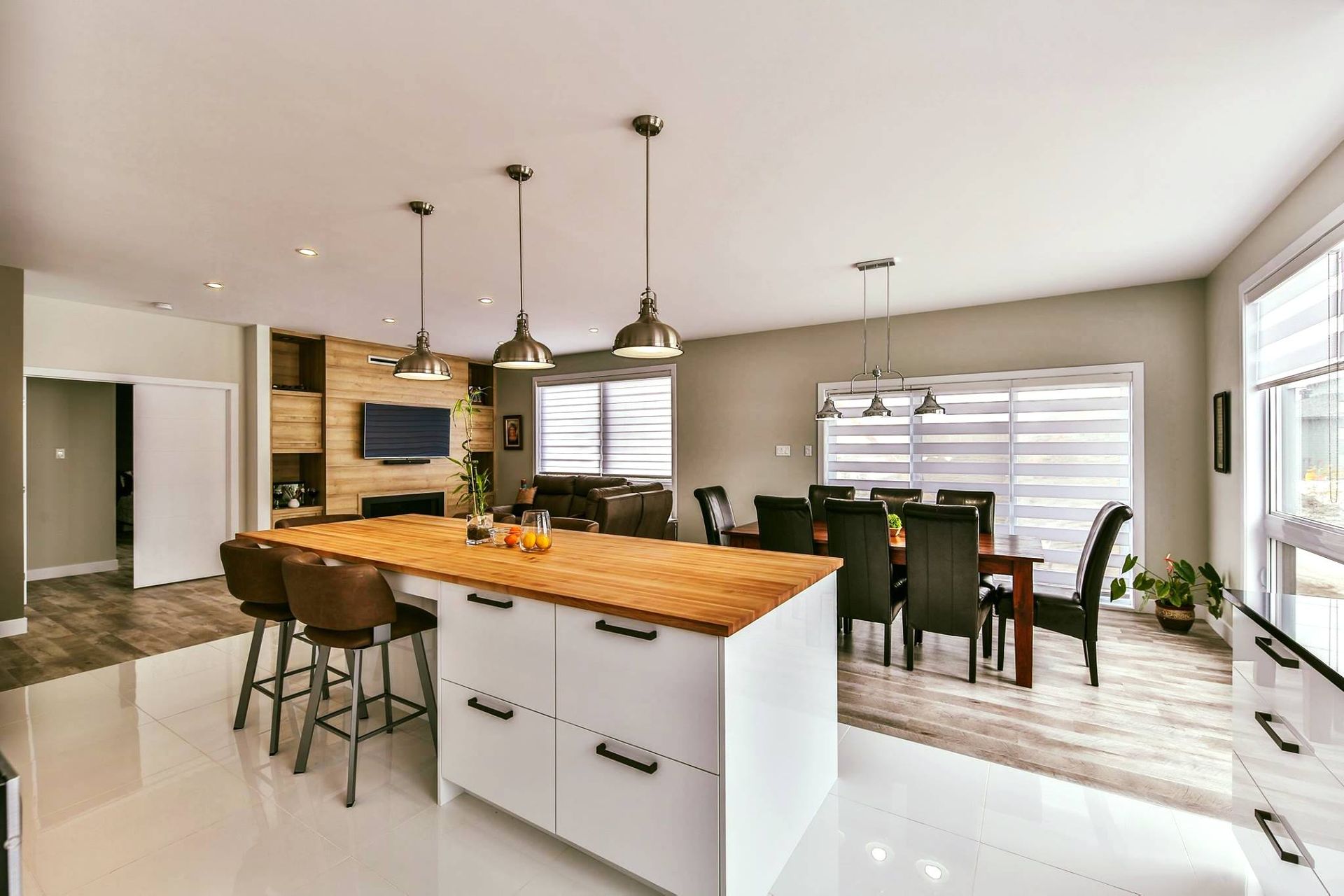 Cuisine/salle à manger à aire ouverte avec un grand îlot, des accents de bois, des luminaires suspendus et une table à manger en bois foncé.