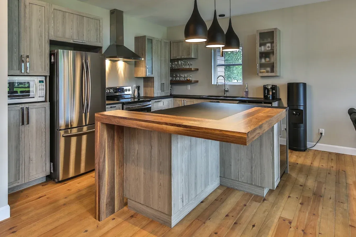 Cuisine moderne avec armoires en bois et grises, appareils électroménagers en acier inoxydable et îlot en bois.