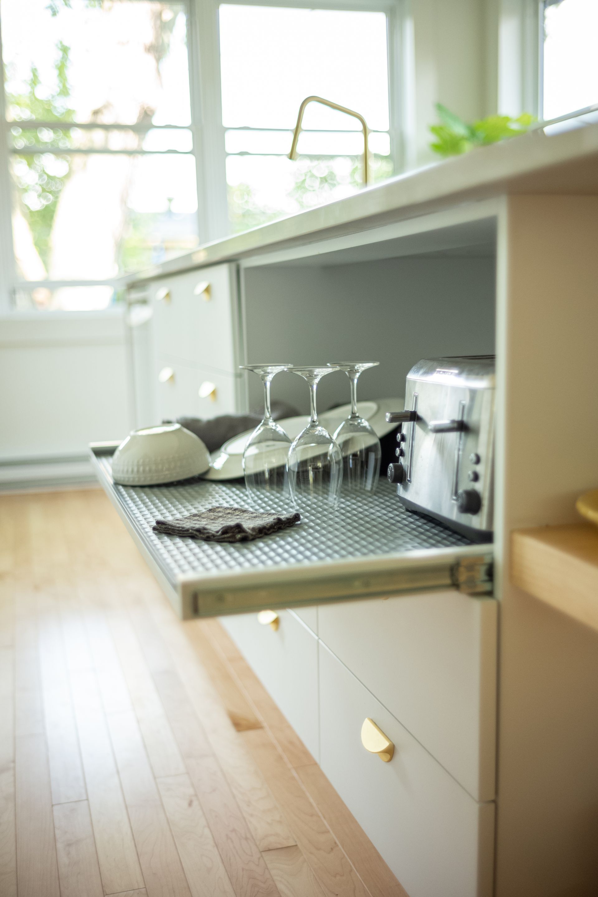 Îlot de cuisine blanc avec un tiroir retiré, contenant des verres et un grille-pain.