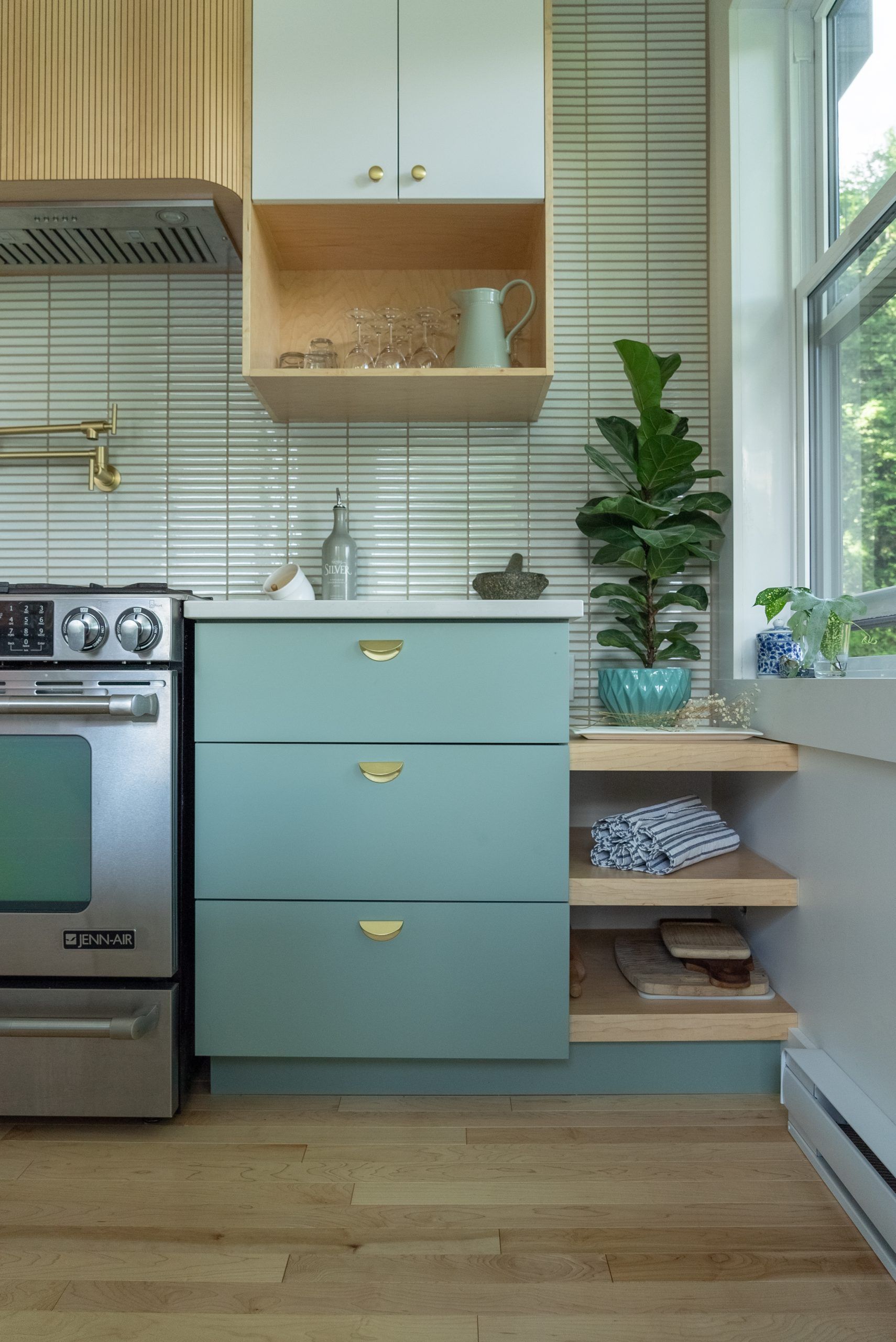 Une cuisine avec une armoire bleu clair, un four en acier inoxydable et un dosseret en carrelage vert.