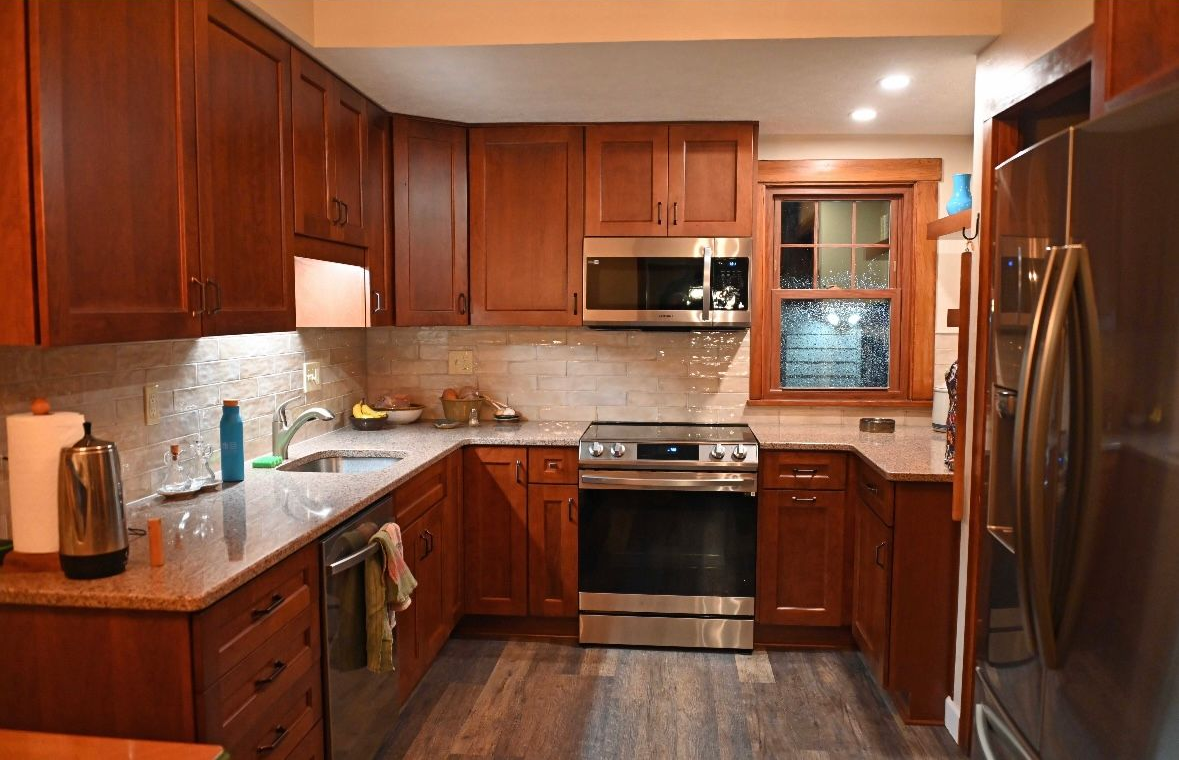 A kitchen with dark wood cabinets, stainless steel appliances, and a gray countertop.