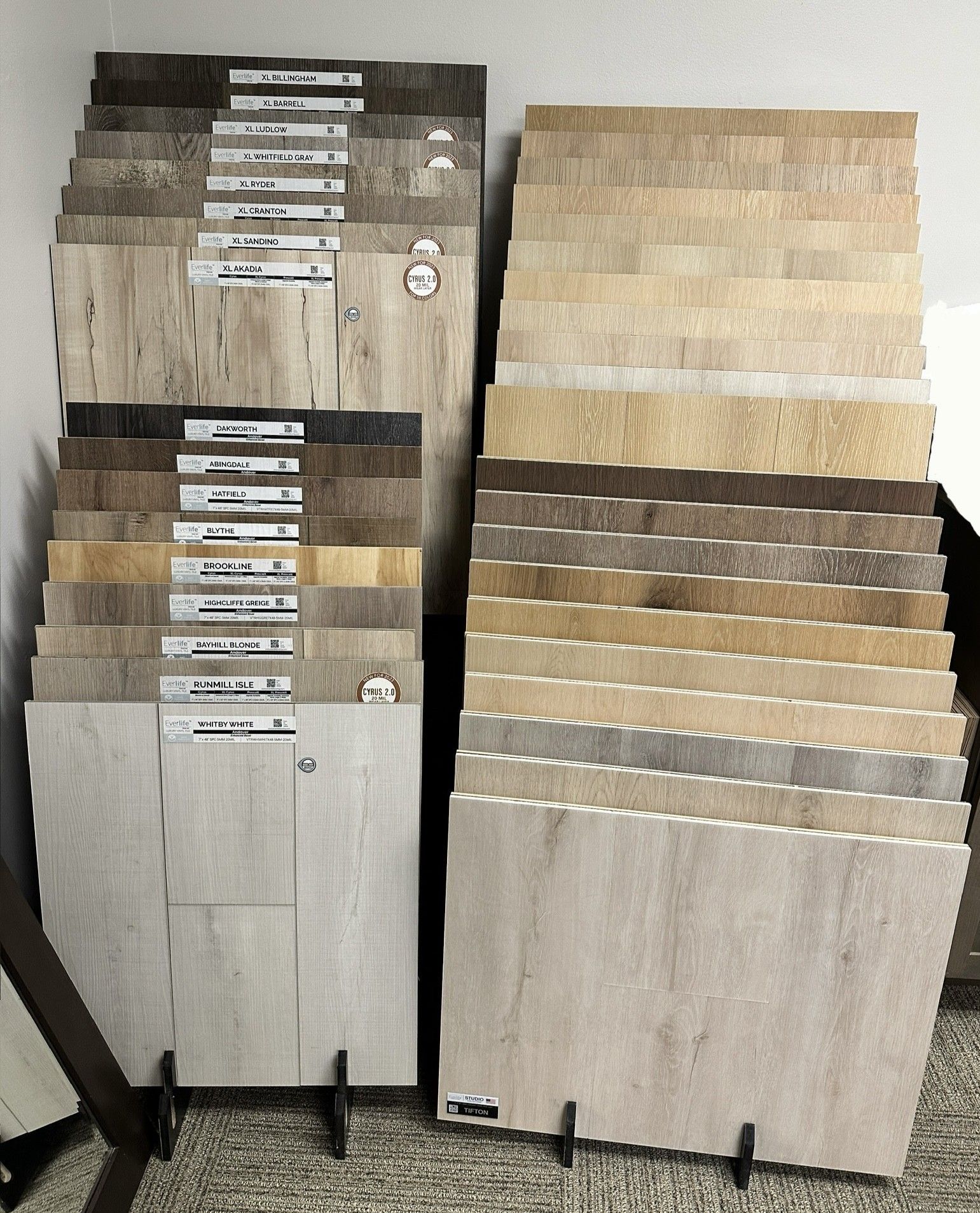 Displays of flooring samples in various shades of brown and tan, in a showroom setting.