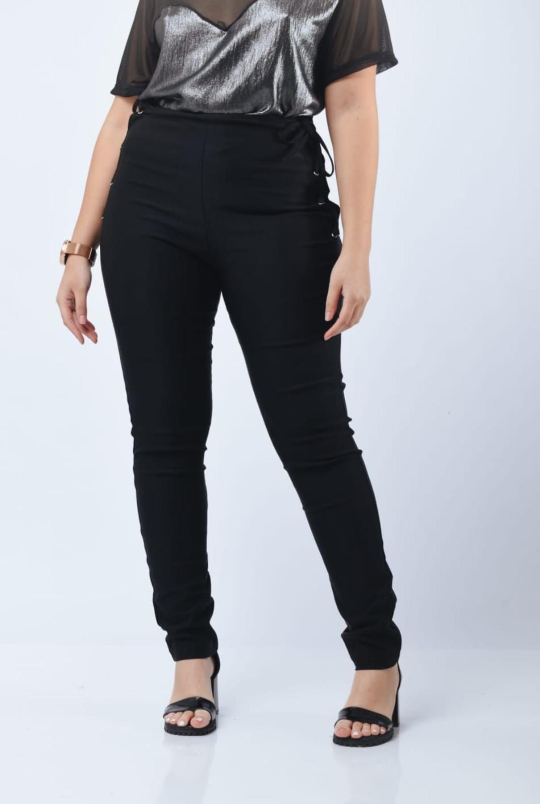 Una mujer con un sujetador deportivo negro y mallas negras está en cuclillas