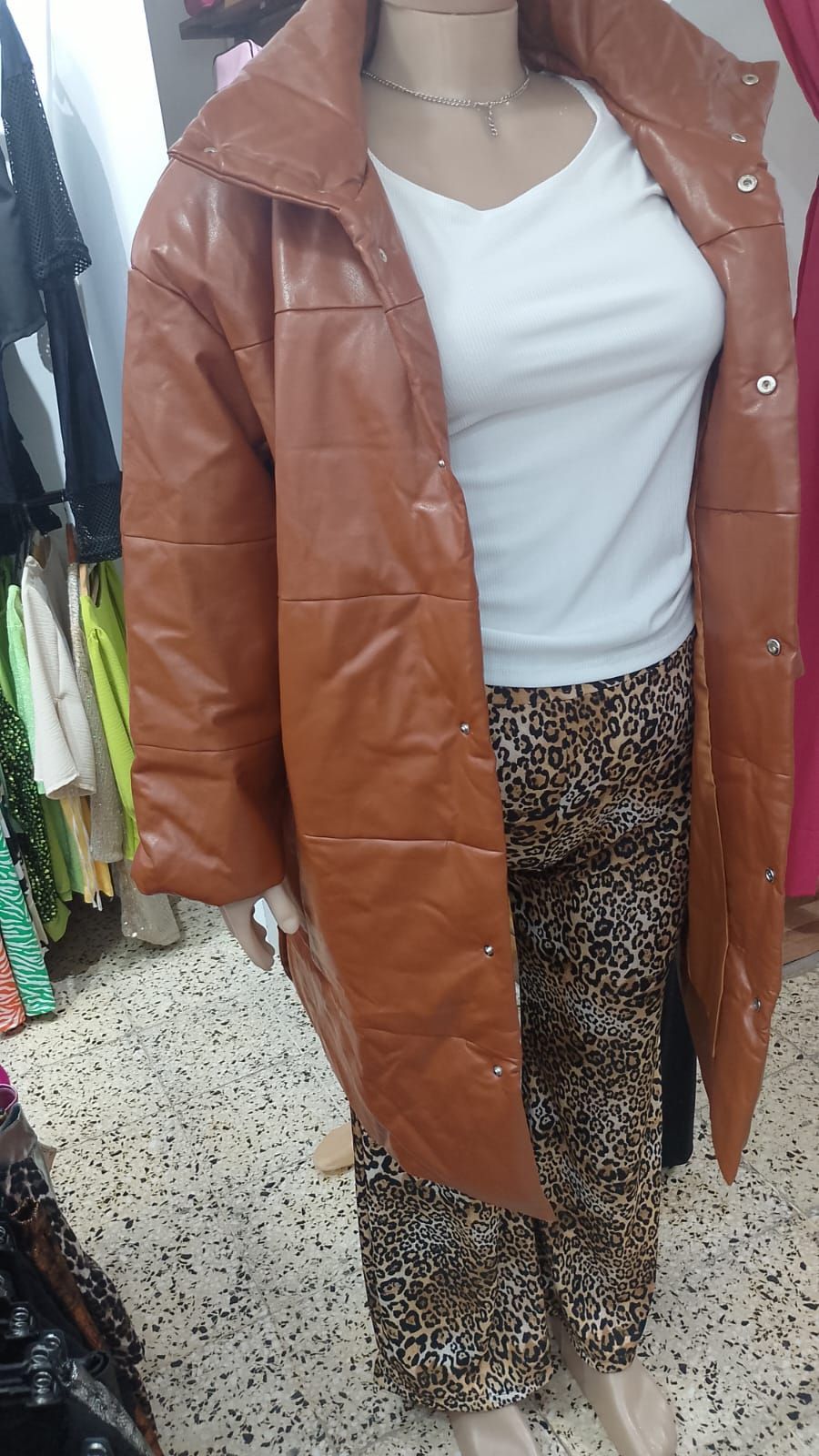 Una mujer lleva una chaqueta de cuero marrón y pantalones con estampado de leopardo.