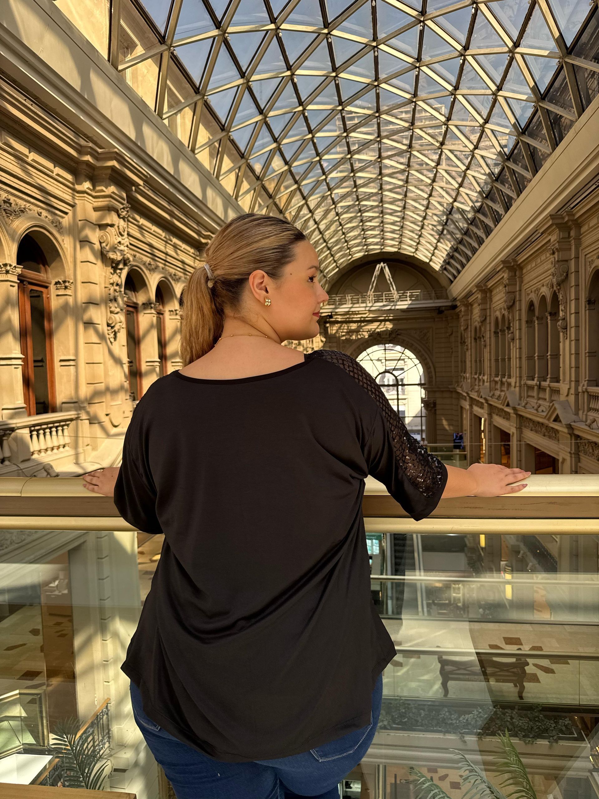 Una mujer con una camiseta negra está parada en un edificio.