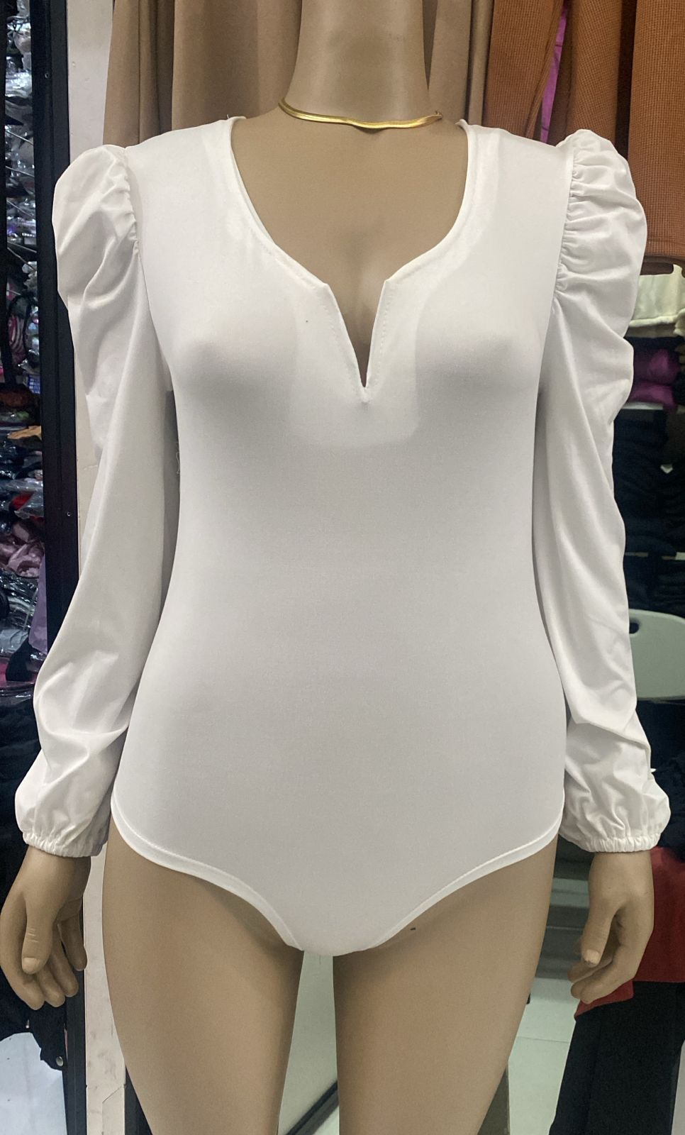 Body de color canela sobre maniquí con escote pronunciado y mangas abullonadas.