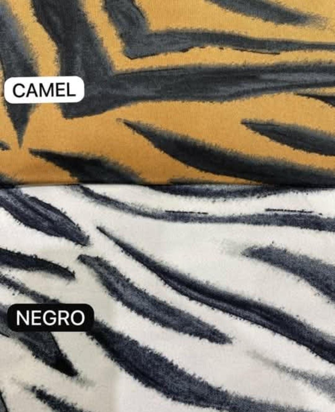 Una mujer con un top con estampado de cebra se apoya en una estructura geométrica negra.