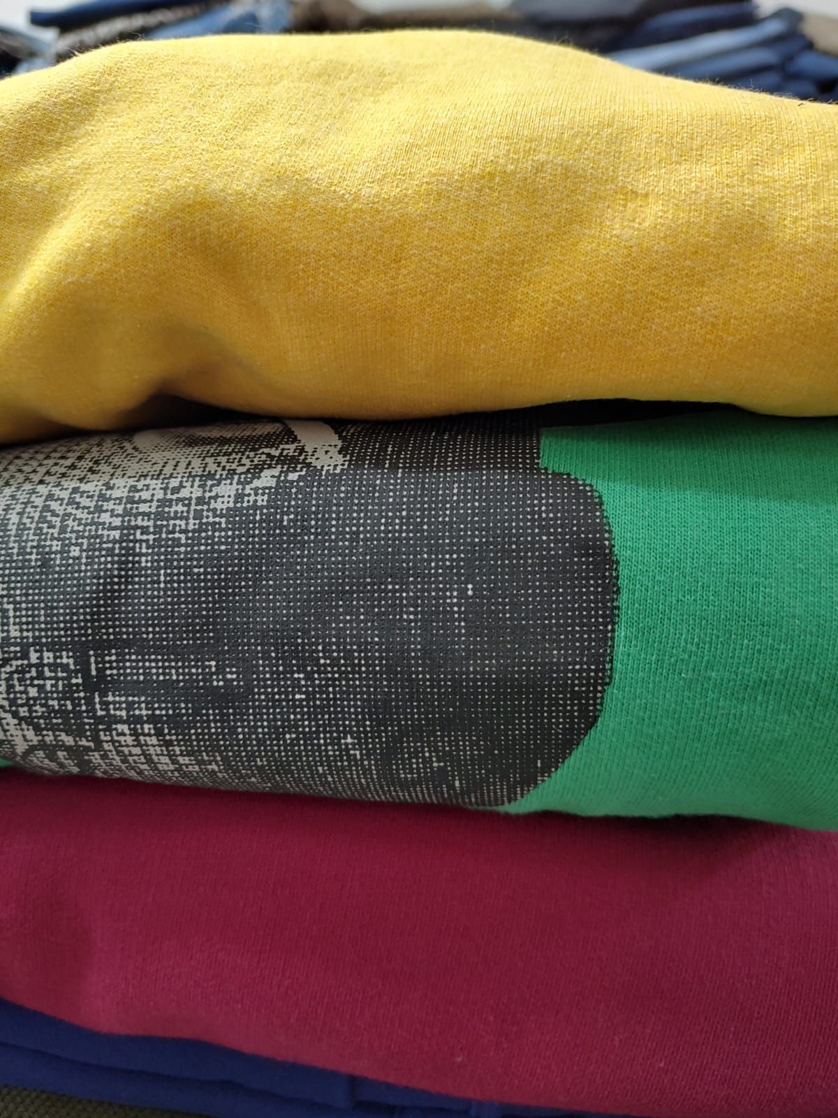 Persona con sudadera rosa junto a un lago, mirando hacia el agua. Gráfico impreso en la espalda. Cielo azul.