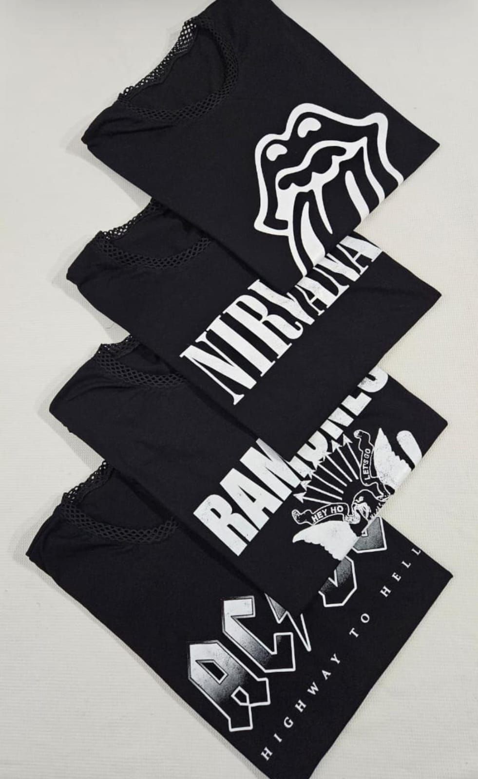 Mujer que lleva una camiseta negra de ACDC con mangas y dobladillo de rejilla, sonriendo.