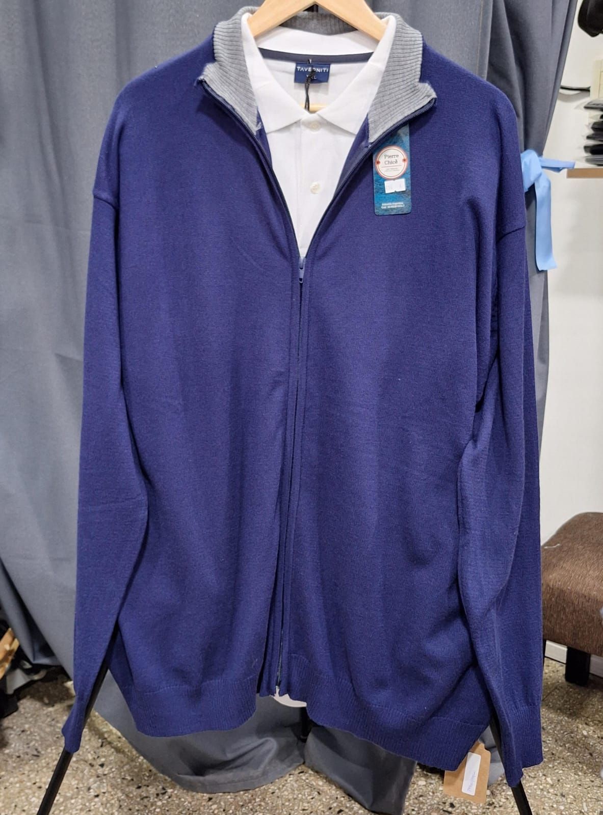 Tres suéteres, gris y azul marino, cuelgan de un perchero de madera.