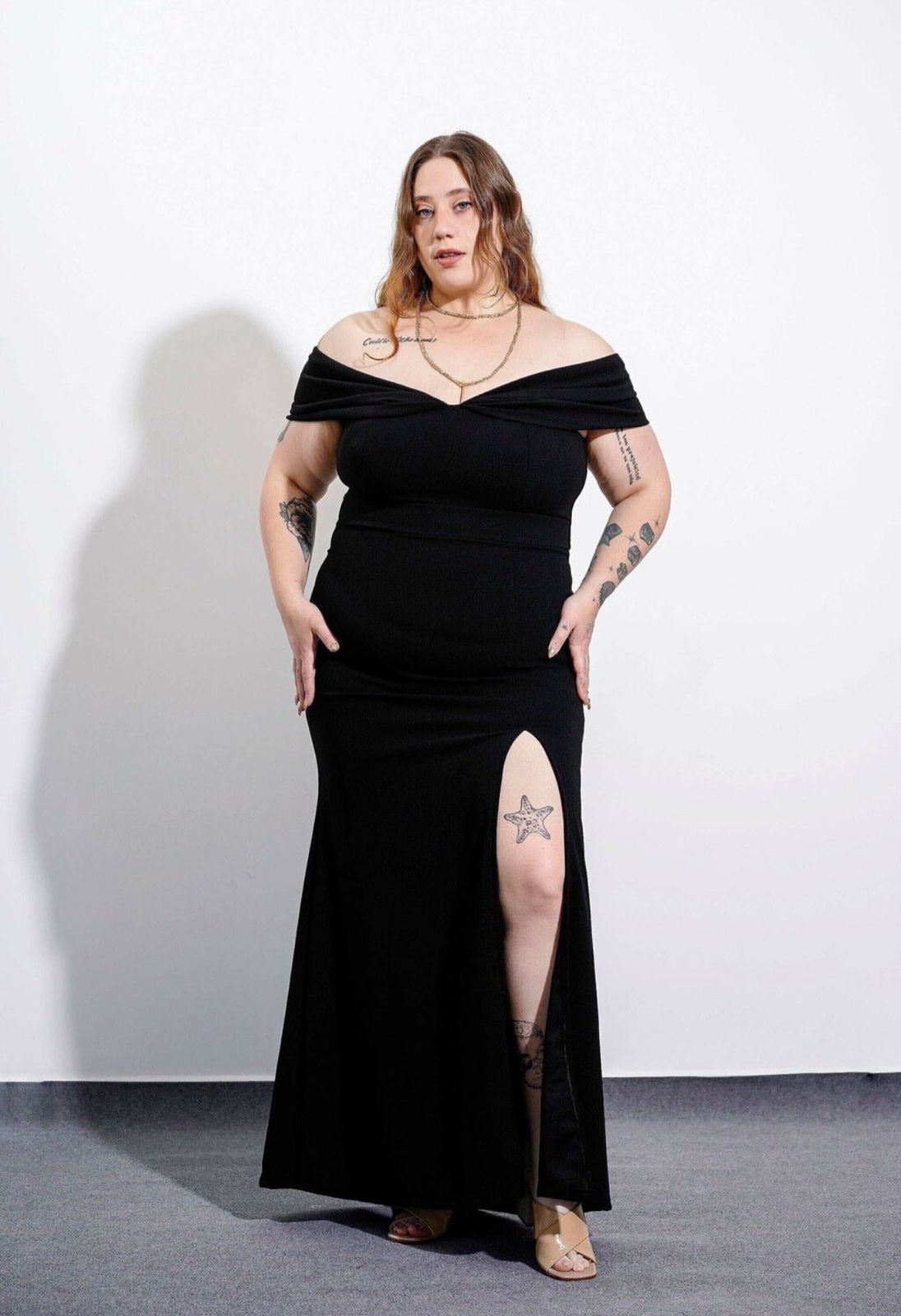 Maniquí con vestido azul con abertura, detrás cuelgan otros vestidos de colores.