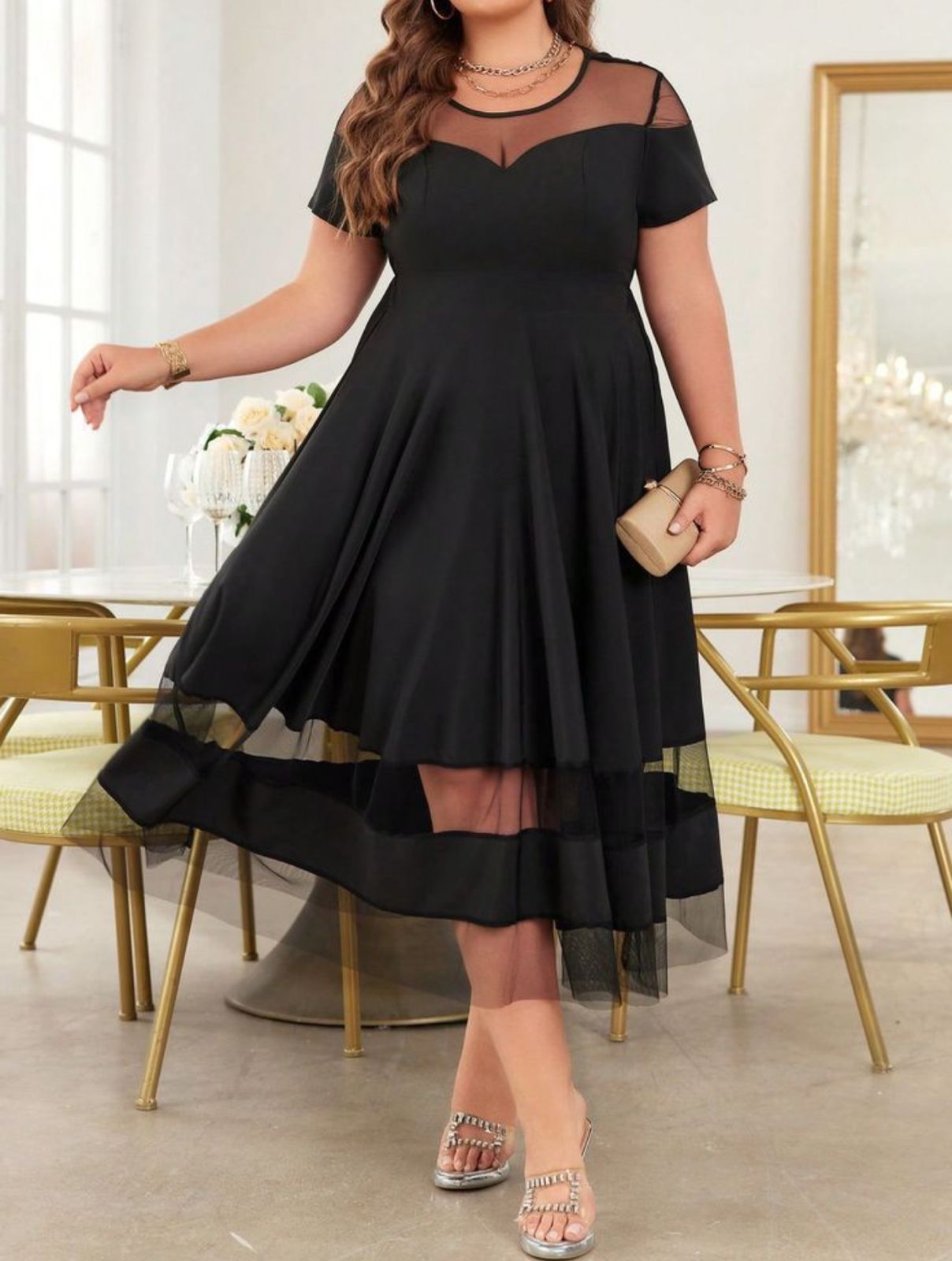 Mujer vestida de negro, con un bolso de mano, parada frente a un edificio. Puerta, letrero 