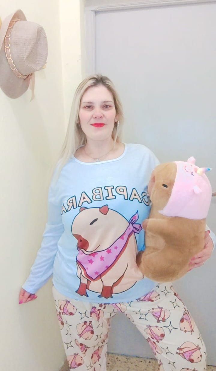 Mujer en pijama sosteniendo un animal de peluche; de ​​pie en una puerta.