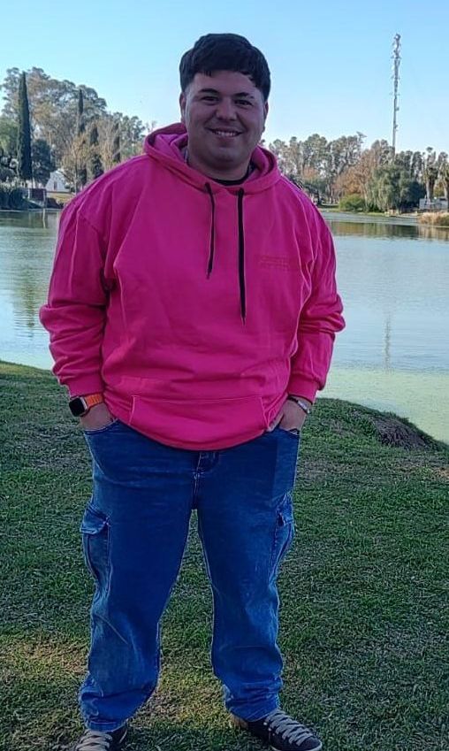 Una persona con una sudadera con capucha rosa y pantalones vaqueros