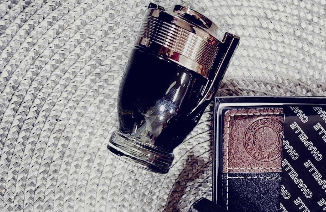 Frasco de perfume sobre tela texturizada y superficie marrón.