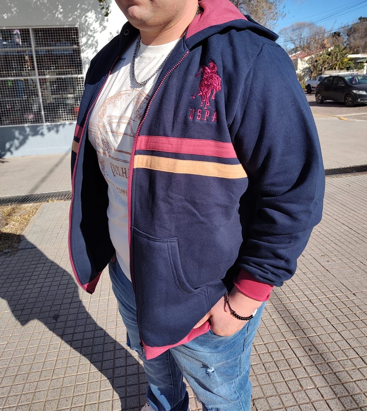 Hombre con una chaqueta azul mirando fuera de cámara en una calle soleada.