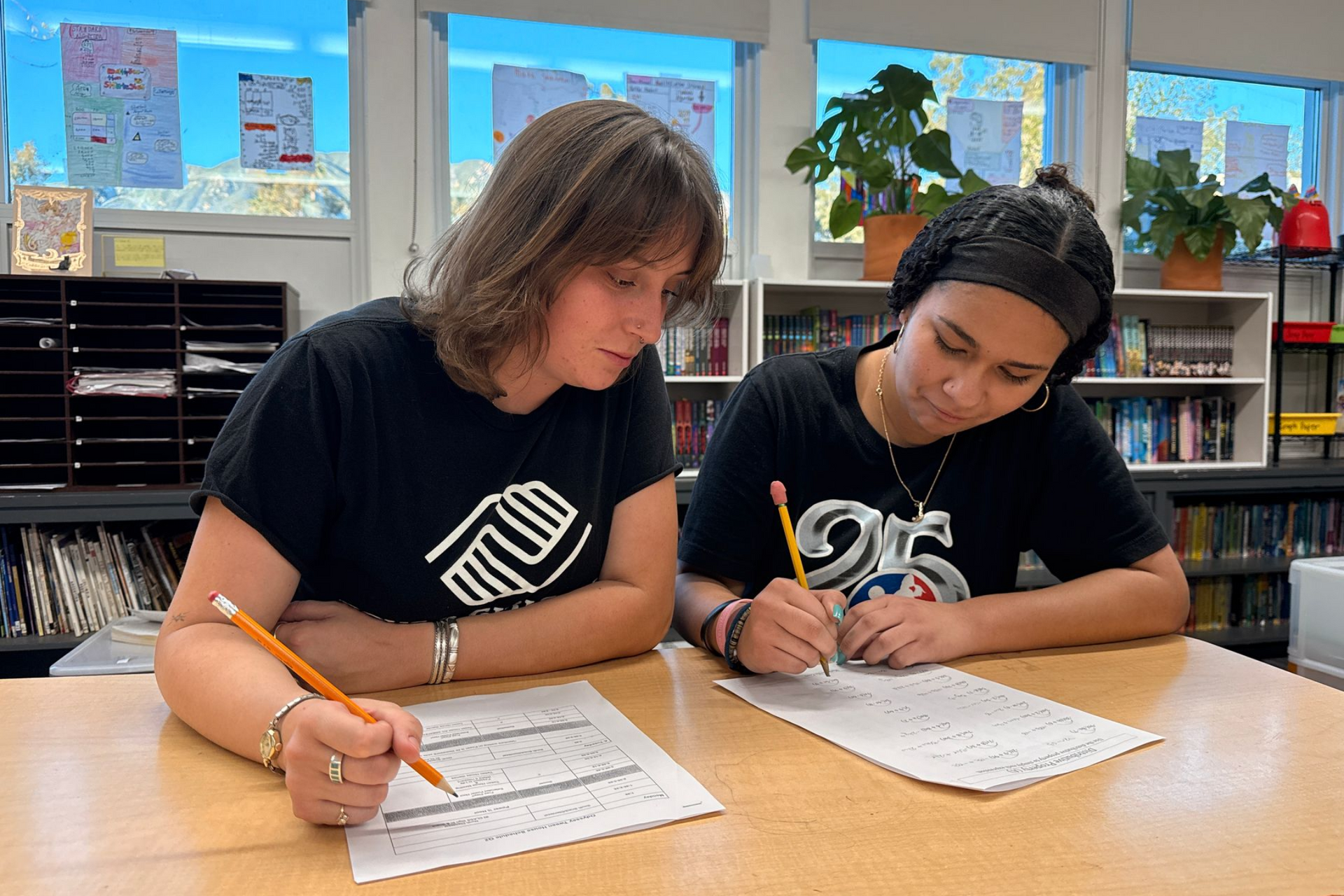 Counselor with boy child posing at a table with pink door behind them.