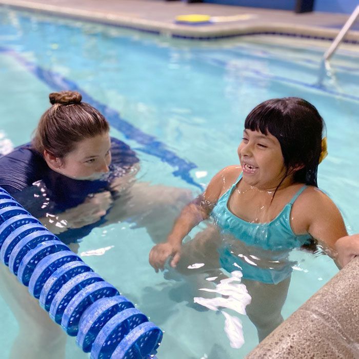 Counselor with girl child learning to swim