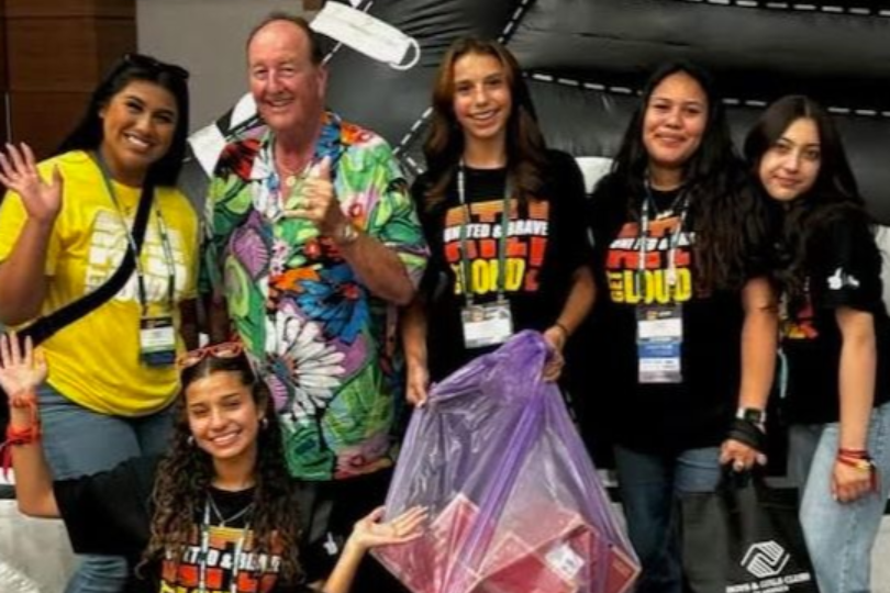 Counselor with boy child posing at a table with pink door behind them.