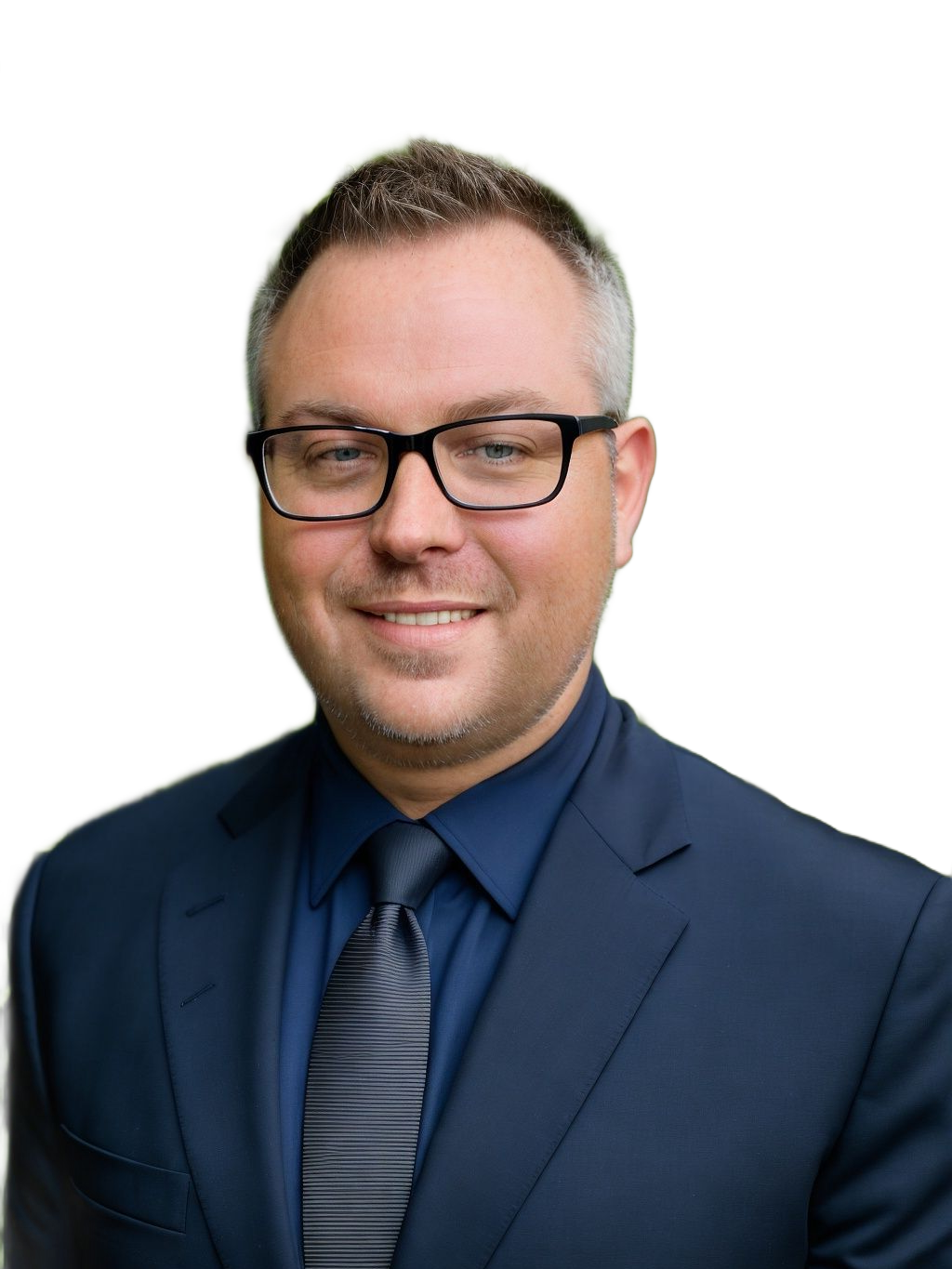 Man in suit and glasses smiling, looking at the camera.