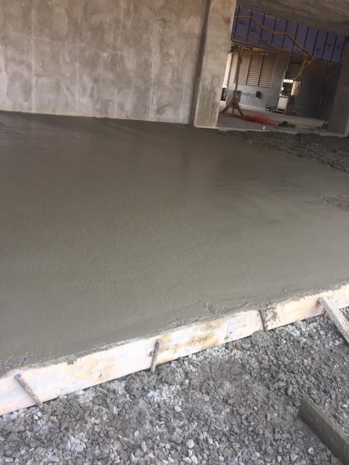 Freshly poured gray concrete floor in a building under construction.