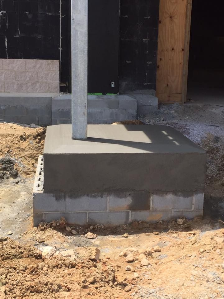 A concrete base with a metal pole in the middle, set on concrete blocks at a construction site.