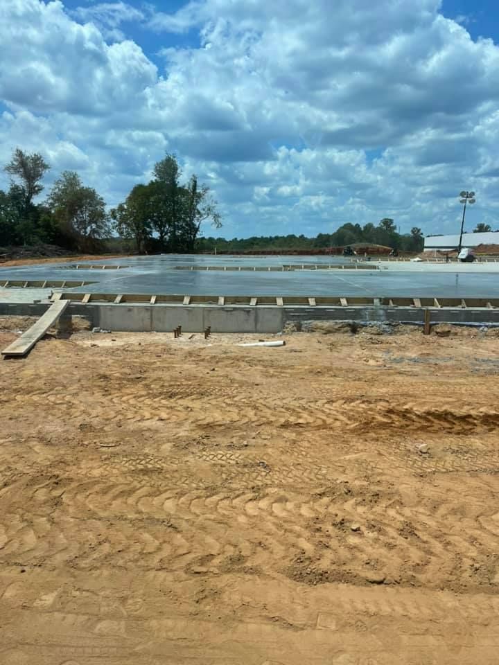 Construction site with a concrete slab, wooden forms, and cloudy sky.