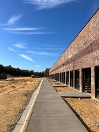 Brick building with walkway under blue sky, construction site.