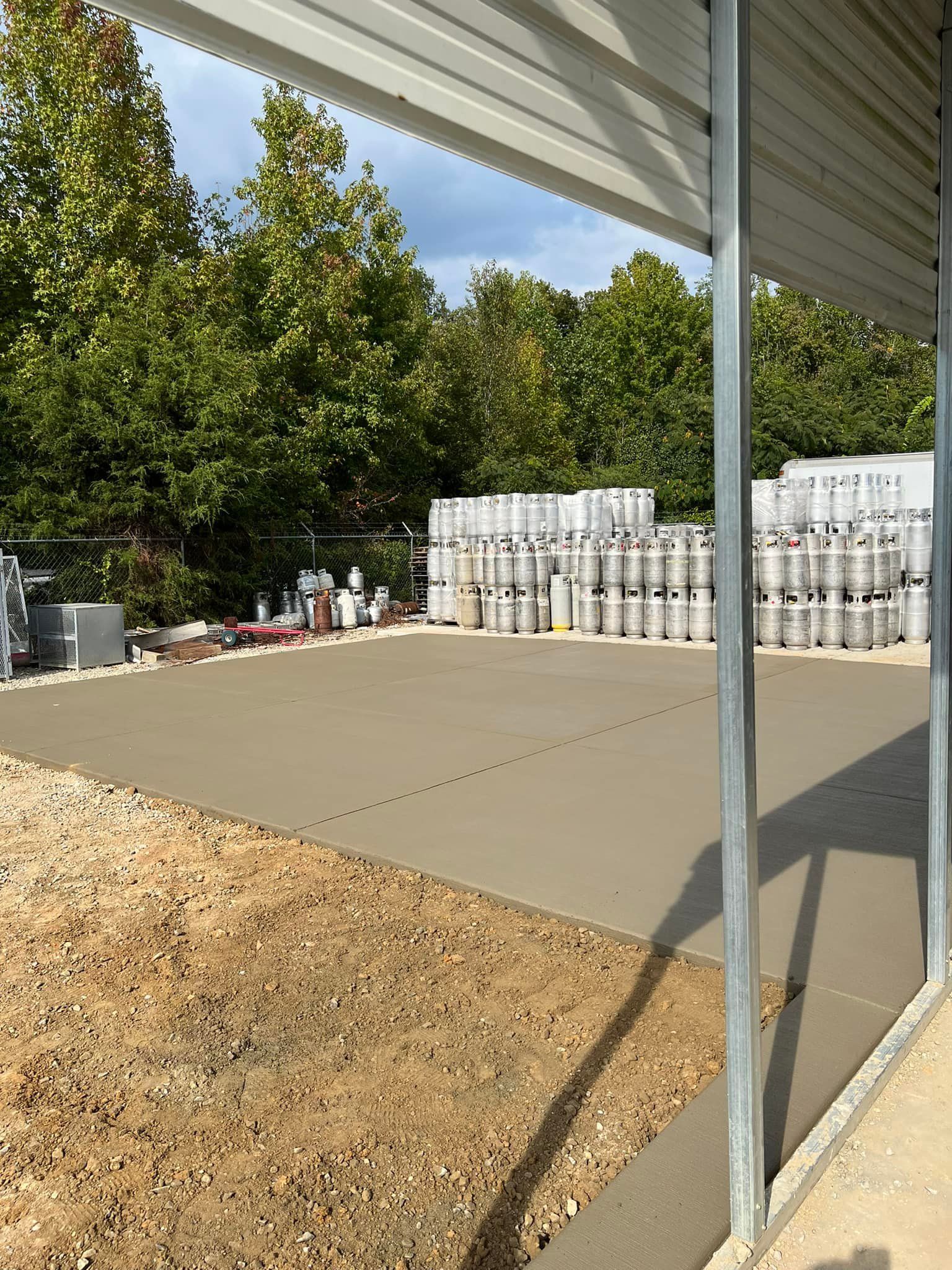 Concrete pad under metal awning, stacks of propane tanks in the background.