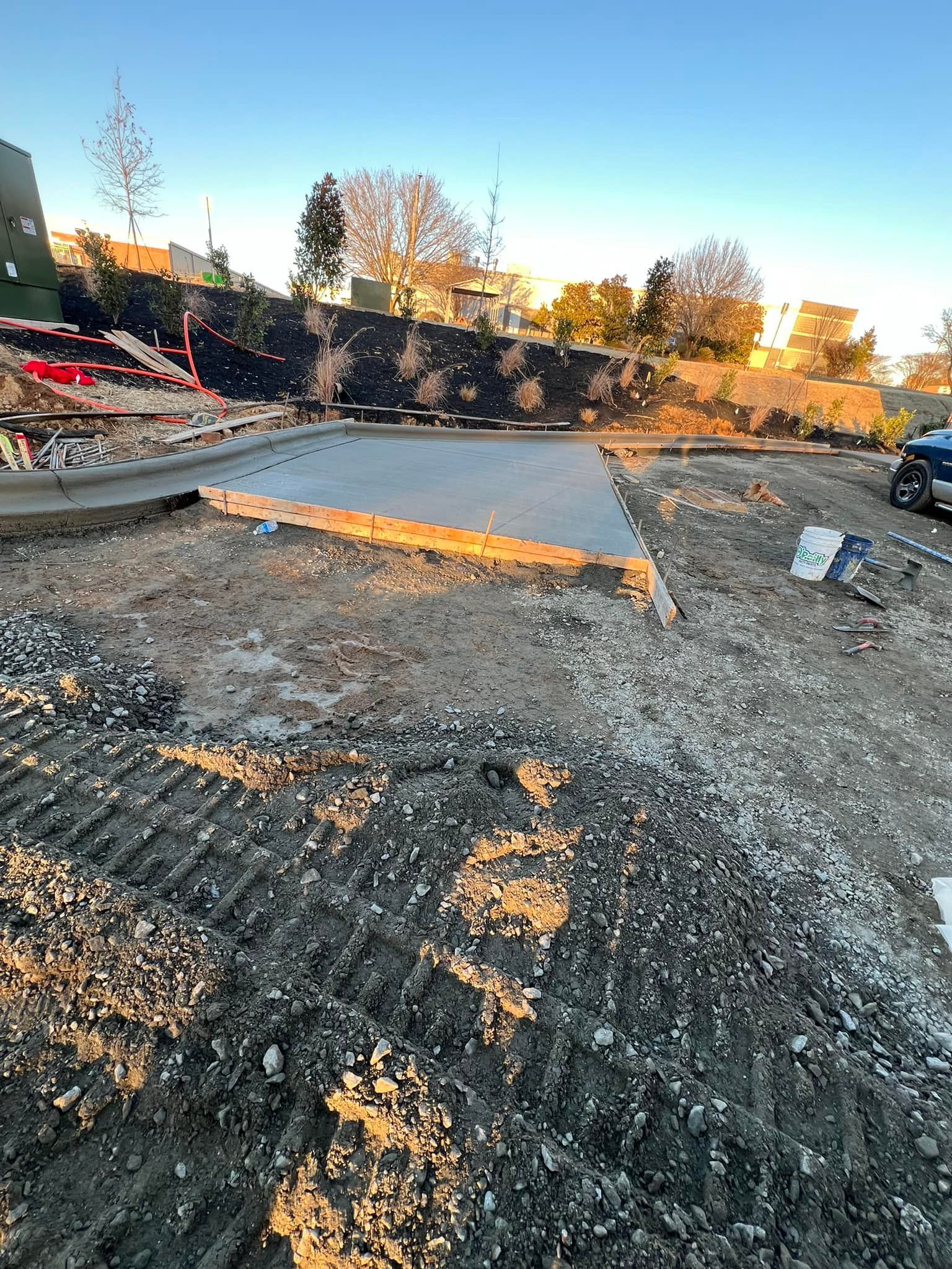 Construction site with a concrete foundation, dirt, and retaining wall.