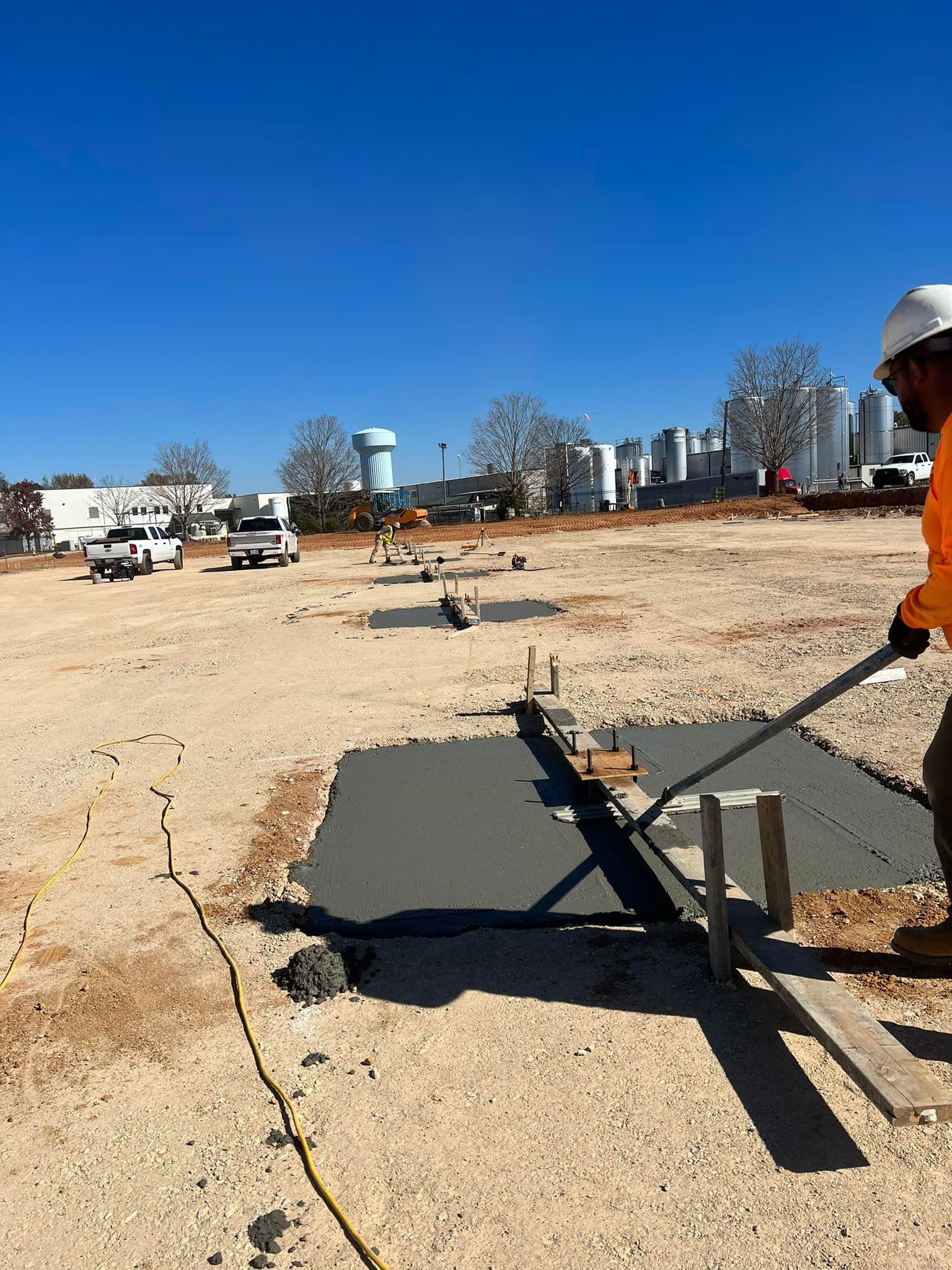 Construction worker smoothing wet concrete with a tool on a construction site.
