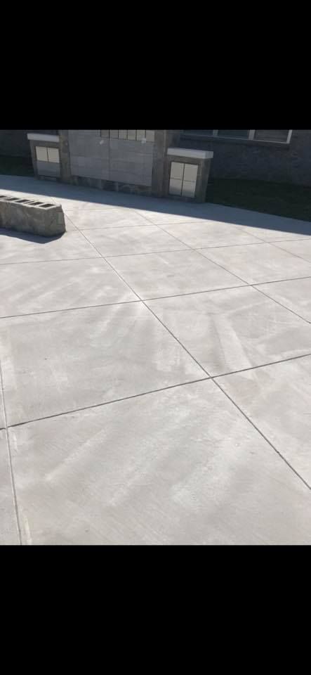 Concrete patio with cut lines and a stone structure.