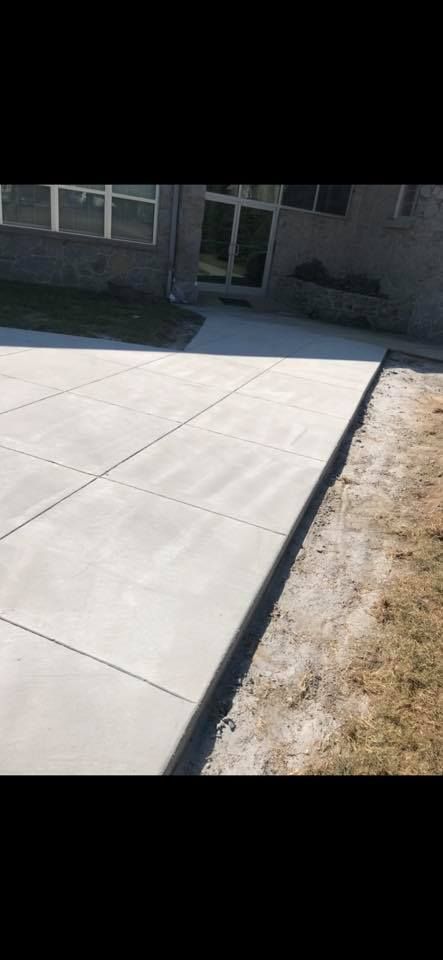 Concrete sidewalk leading to a building with a glass door. Gravel and grass border the path.