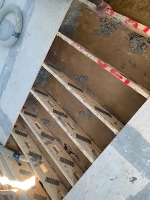 Chevrons en bois exposés sous une surface de couleur claire, peut-être un plancher ou un plafond.