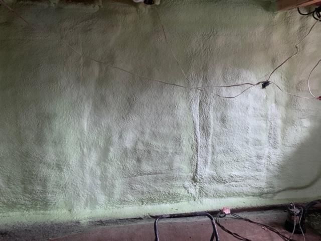 Un mur de sous-sol vert clair avec des stries verticales et des fils exposés.