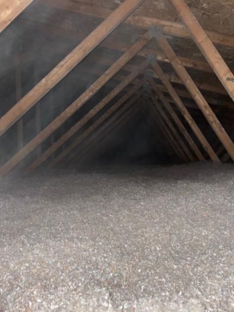 Intérieur d'un grenier, montrant des chevrons en bois et une isolation.