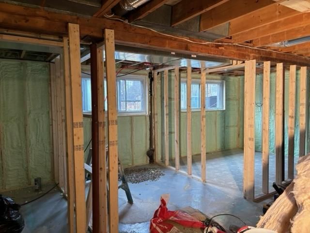 Charpente intérieure du sous-sol, travaux en cours. Montants en bois, isolation, fenêtres, plancher en béton.